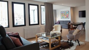 En moderne stue med et glasbord, en sofa, en lænestol, en cowhide- måtte og et spiseområde med bord og stole.
