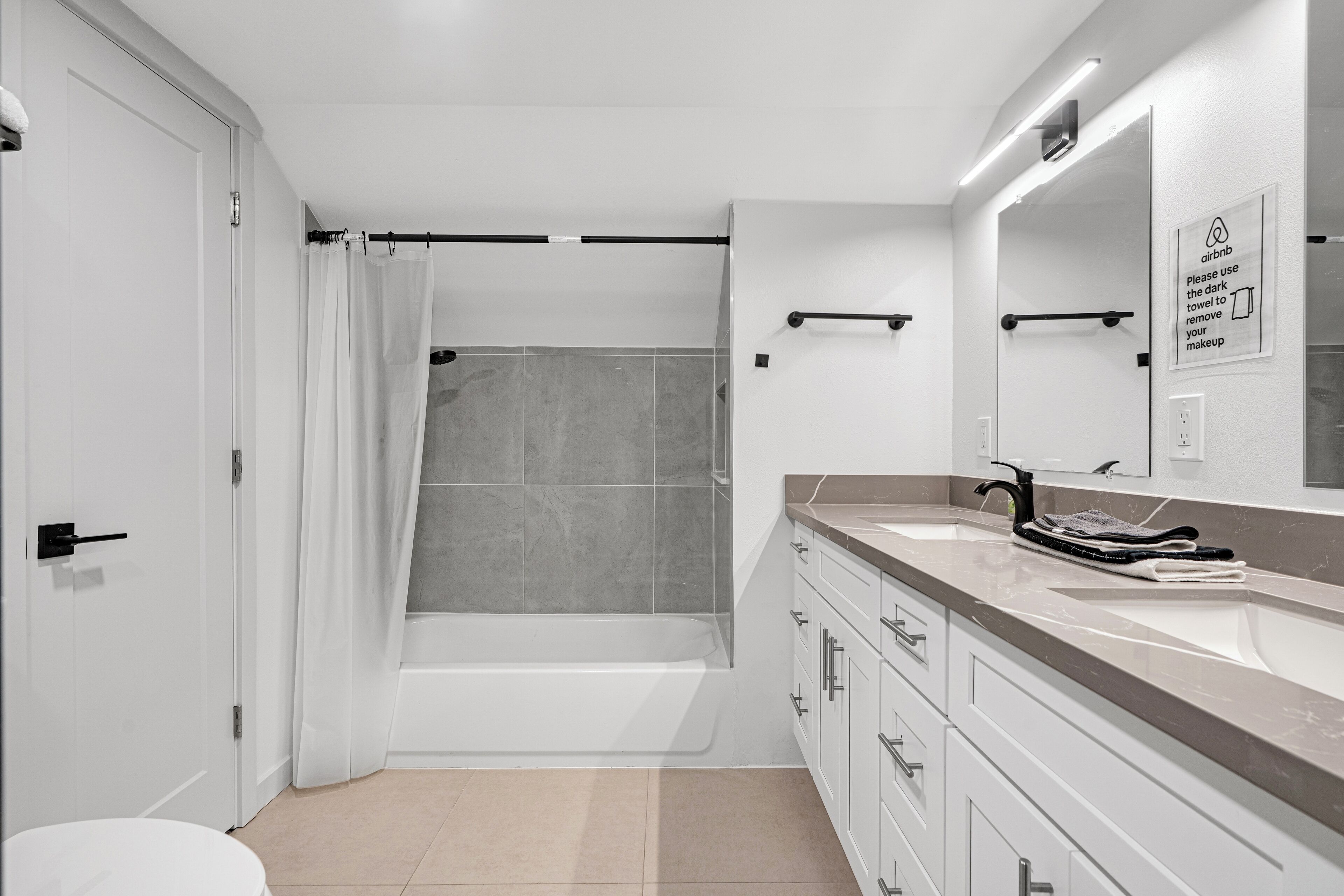 A modern bathroom with a bathtub, a toilet, and a sink with a towel rack.