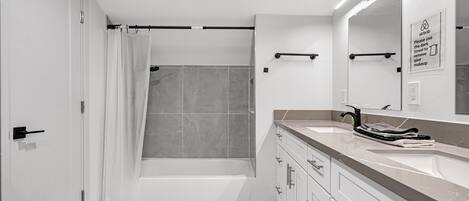 A modern bathroom with a bathtub, a toilet, and a sink with a towel rack.