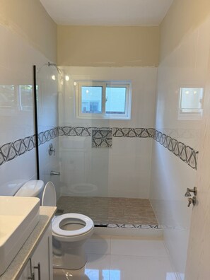 A bathroom with a toilet, a shower, and a window. - 3-bedroom townhome in amazing Ocho Rios with Pool access, Private Gazebo,Balcony (Ocho Rios)