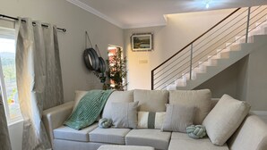 Una sala de estar con un sofá, un reposapiés y una escalera.