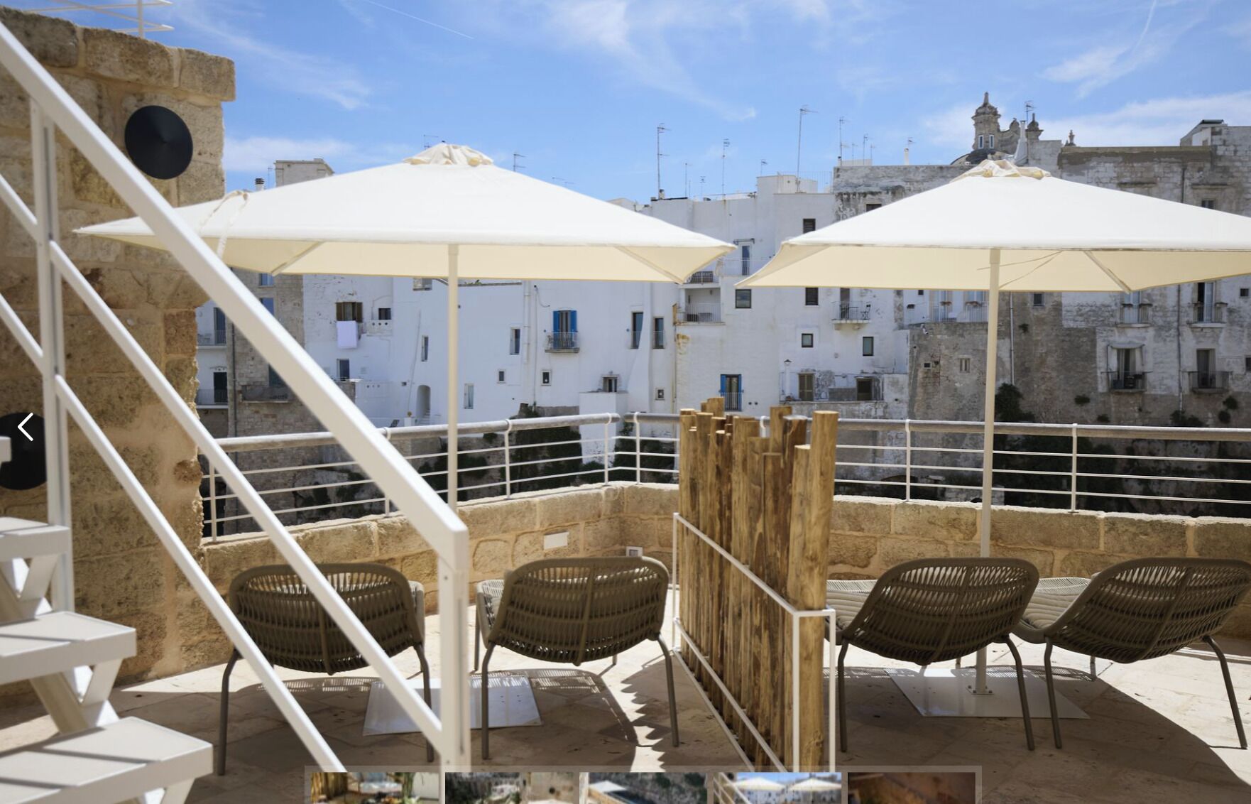 Una terraza en la azotea con asientos al aire libre, sombrillas blancas y vistas a edificios históricos.