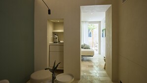 A modern interior with a kitchen area, a seating area with a sofa and cushions, and a small round table with a vase. - Musae In Lama (Polignano a Mare)