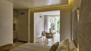 A hotel room with a bed, a sitting area with a table and chairs, and a view of the outdoors.