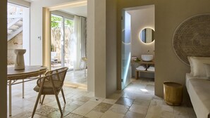 A modern interior with a dining area, a sofa, and a bathroom with a mirror and sink. - Musae In Lama (Polignano a Mare)