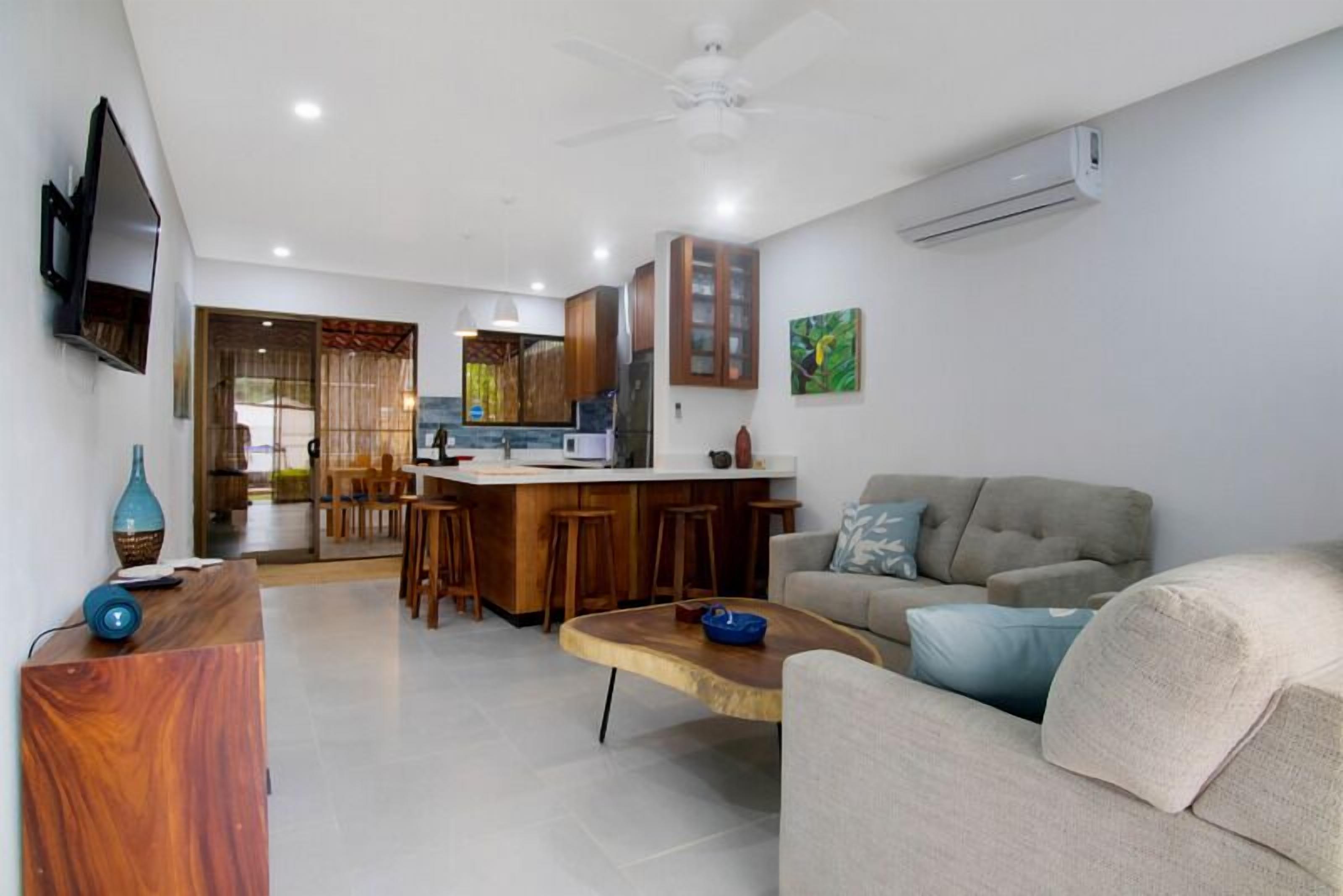 A modern living room with a sofa, a coffee table, and a kitchen area in the background.