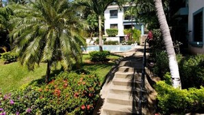Un resort con piscina, palmeras y un camino que lleva a un edificio.