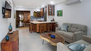 Una cocina moderna con armarios de madera, una isla central con taburetes y un comedor.