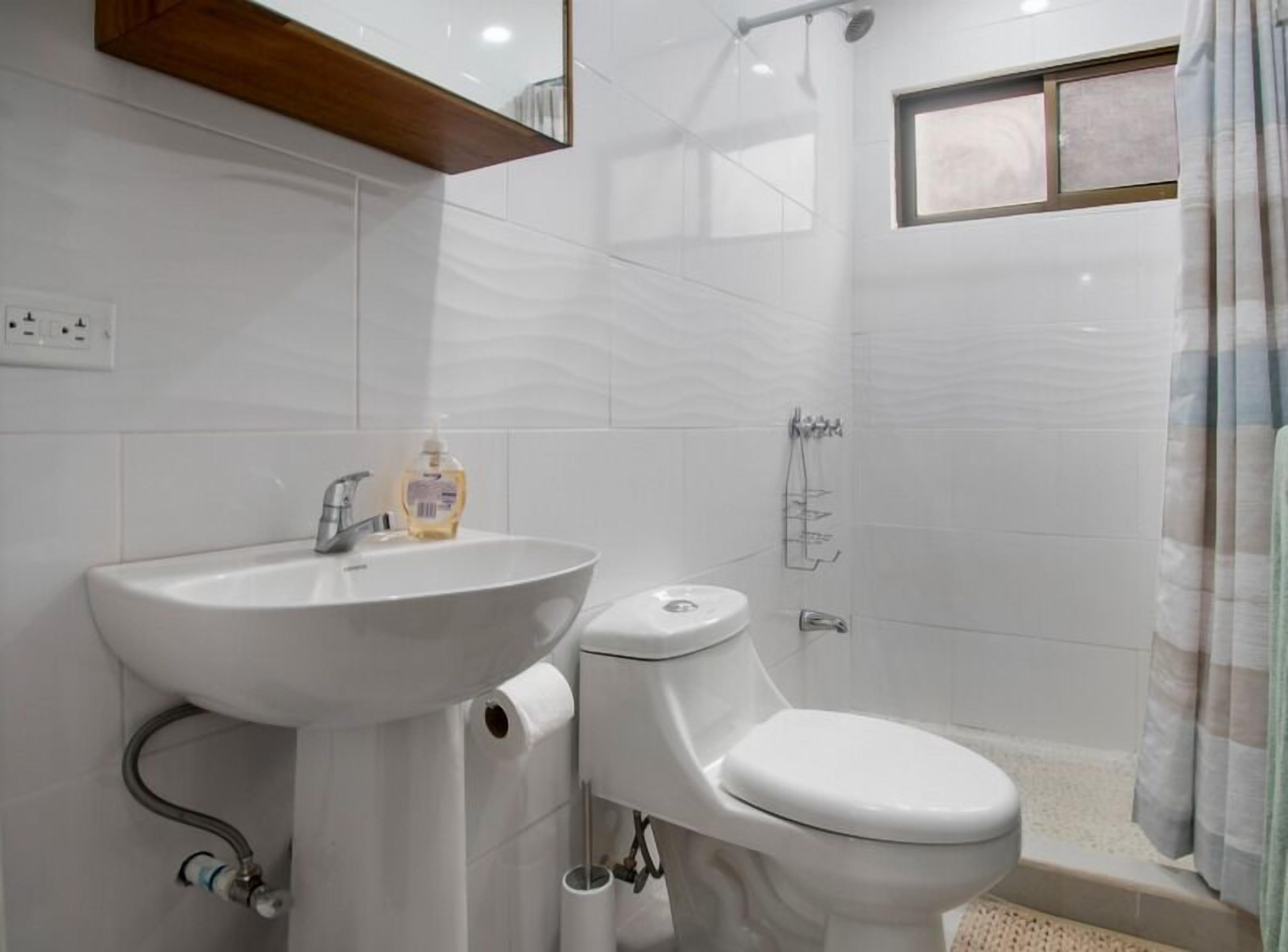 A modern bathroom with a white sink, toilet, and shower.