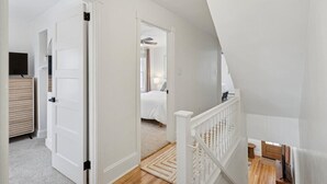 En trappe fører op til et soveværelse med en seng, et natbord og en lampe.