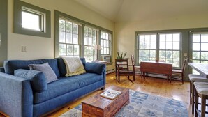 A living room with a blue sofa, wooden coffee table, and a dining area with a wooden table and chairs.