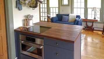Una cocina con mostrador de madera, horno empotrado y ollas colgantes.