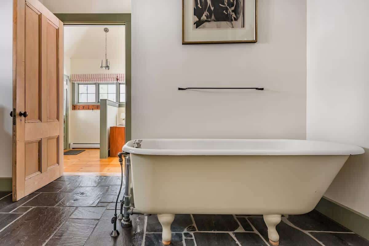 Un bagno con una vasca freestanding, una porta in legno e un quadro appeso al muro.