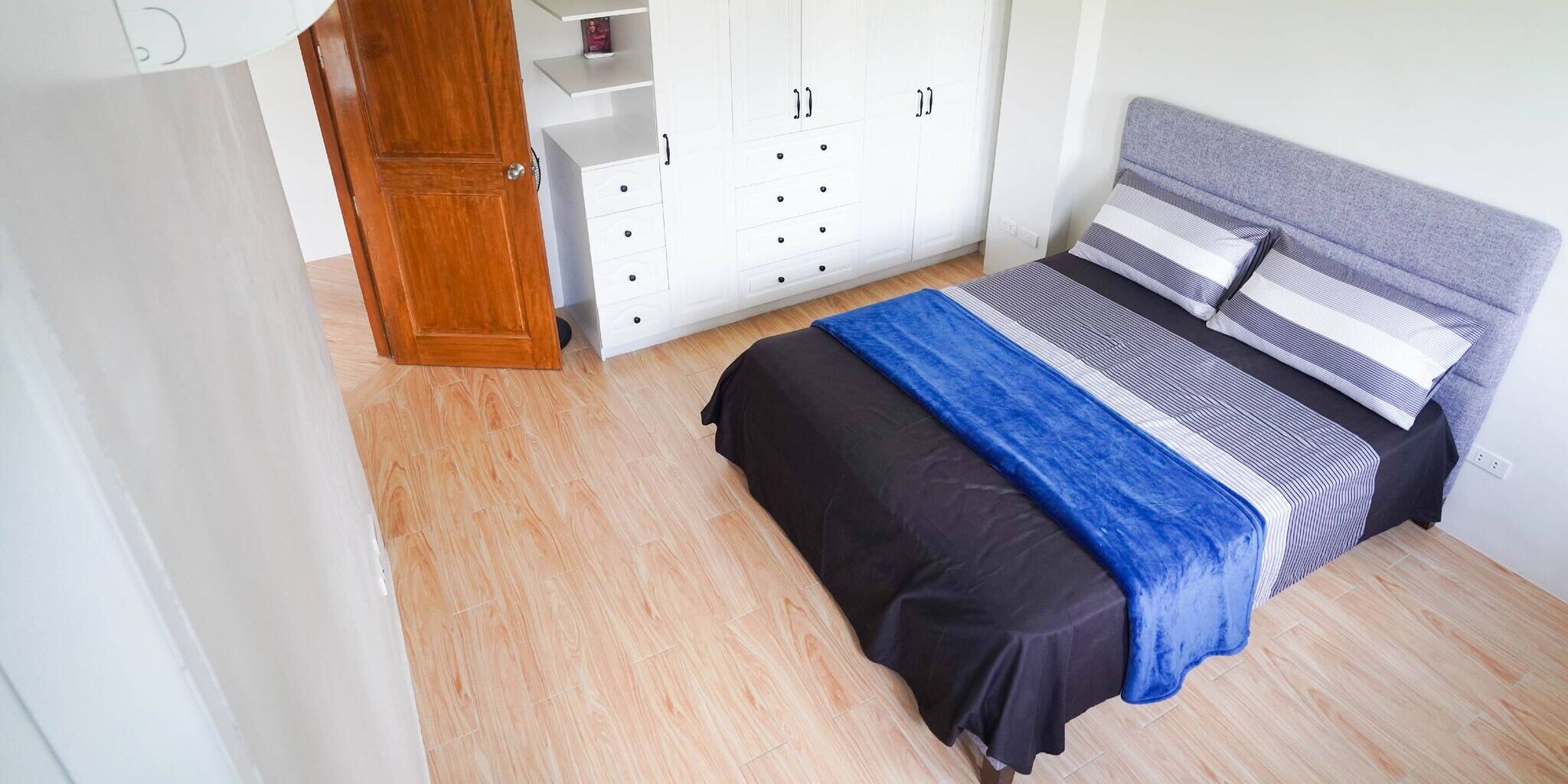 A bedroom with a bed, wardrobe, and a door.