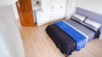 A bedroom with a bed, wardrobe, and a door.