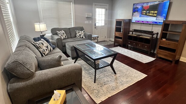 A modern living room with a grey sofa, a glass coffee table, and a flat-screen TV mounted on the wall. - Charming 2-bedroom 2 1/2 bath House with WiFi and AC in fabulous Cincinnati (Cincinnati)