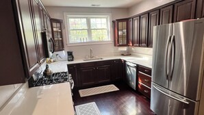 A modern kitchen with dark wood cabinets, stainless steel appliances, and a window providing natural light. - Charming 2-bedroom 2 1/2 bath House with WiFi and AC in fabulous Cincinnati (Cincinnati)