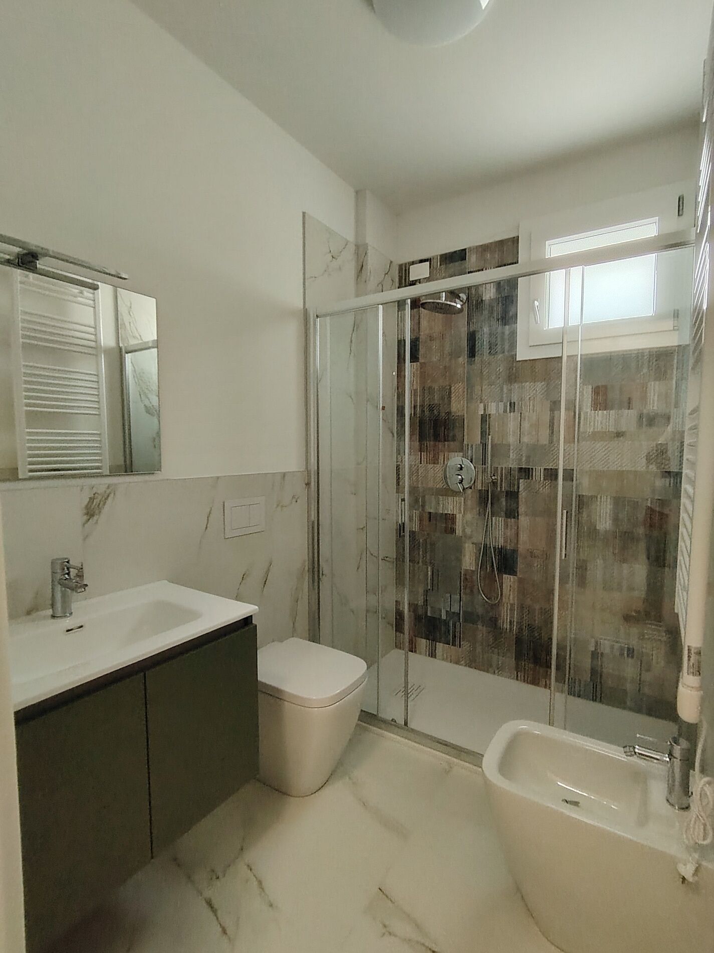 Une salle de bain moderne avec une douche à parois de verre, un lavabo et des toilettes.