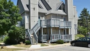 A two-story building with a prominent gabled roof, a central staircase, and a balcony on the second floor. - Artistic Hillside Loft (Blue Mountain)