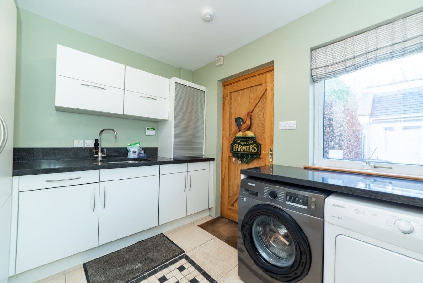 A kitchen with white cabinets, a built-in washing machine, and a door with a sign.