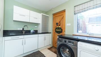 A kitchen with white cabinets, a built-in washing machine, and a door with a sign.