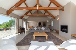 A spacious living area with a high ceiling, a fireplace, and a view of the outdoors.