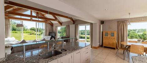 A modern kitchen with granite countertops, a built-in sink, and a dining area with a table and chairs.