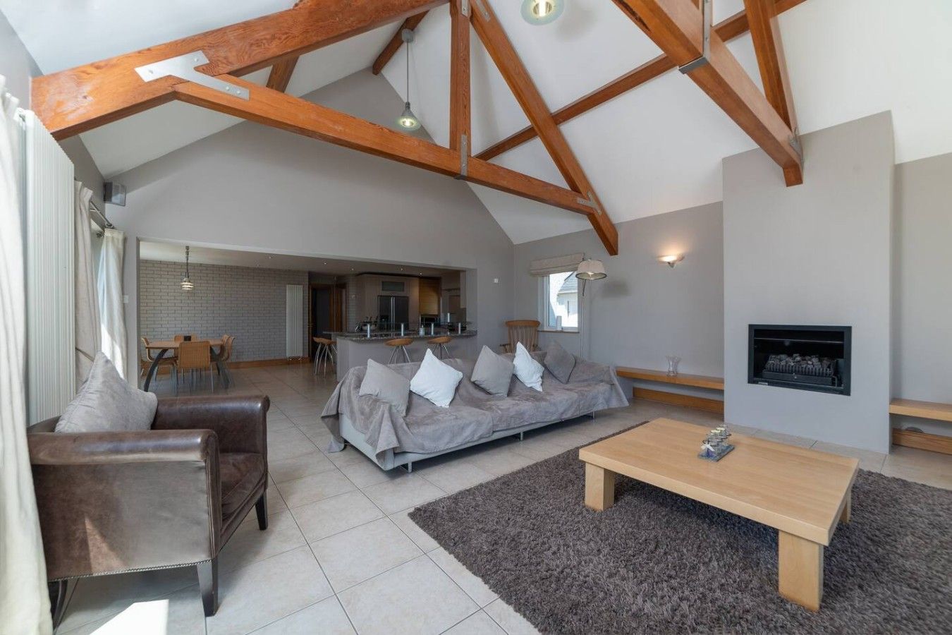 A spacious living room with a high ceiling, a sofa set, a coffee table, and a fireplace.