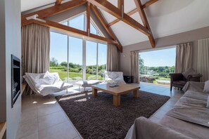 Un ampio soggiorno con soffitto alto, ampie finestre e vista su un rigoglioso giardino.