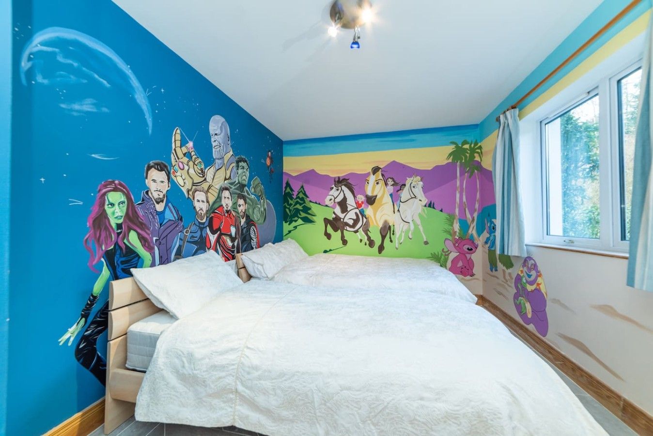 A bedroom with a bed, a mural on the wall, and a window.