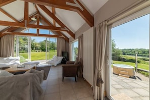A spacious room with a large sliding glass door leading to a garden, a bed, a sofa, and a small table with a television.