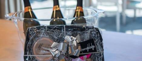 A glass container with three bottles of wine, a wrapped gift, and a small box on a table.