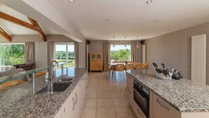 A modern kitchen with granite countertops, a built-in oven, and a dining area with a table and chairs.