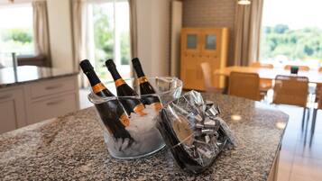 Una encimera de cocina con un balde de vidrio para hielo que contiene botellas, un regalo envuelto y cubitos de hielo.