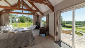A spacious room with a high ceiling, large windows, and a view of a lush garden.