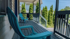 Een houten veranda met twee turquoise stoelen en een kleine tafel.