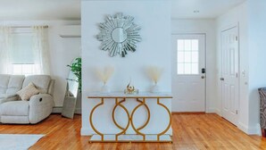 Een moderne woonkamer met een bank, een decoratieve spiegel en een console met vazen.