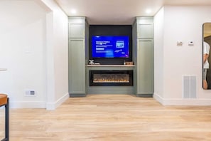 A modern living room with a flat-screen TV, a fireplace, and built-in cabinets.
