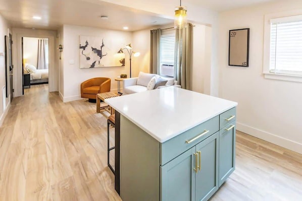 A modern kitchen with a central island, light blue cabinets, and a white countertop.