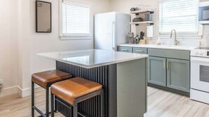Una cocina moderna con una isla central, taburetes de bar y horno empotrado.