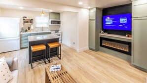 Una cocina moderna con microondas integrado, una zona de bar con taburetes, un televisor de pantalla plana y una chimenea.