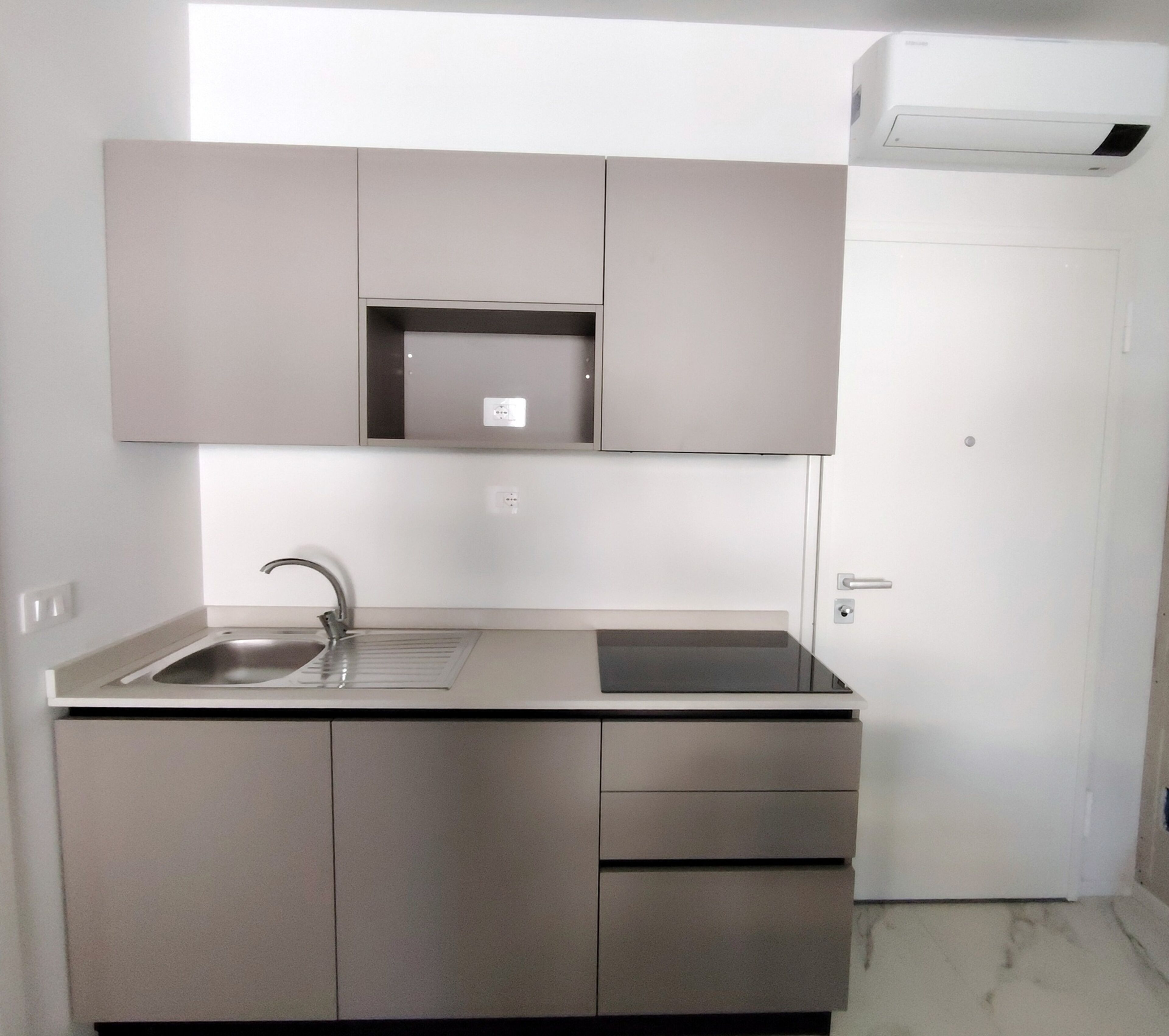 A modern kitchen with a stainless steel sink, cabinets, and a built-in microwave.