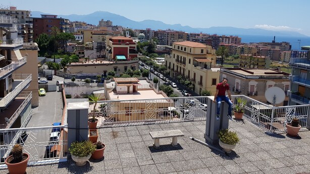 A rooftop terrace with potted plants, a stone bench, and a view of the cityscape and mountains. - CasaCondo on Golden Mile - Twin Apartments by UNESCO Wonders for Large Groups (Torre del Greco)
