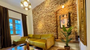 A living room with a brick wall, a yellow sofa, a glass coffee table, and a brown ottoman. - Mansion Istanbulite (Istanbul)
