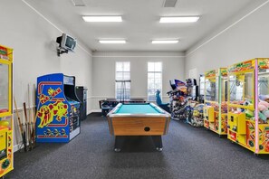 Quarto com mesa de bilhar, jogos de fliperama e televisão.