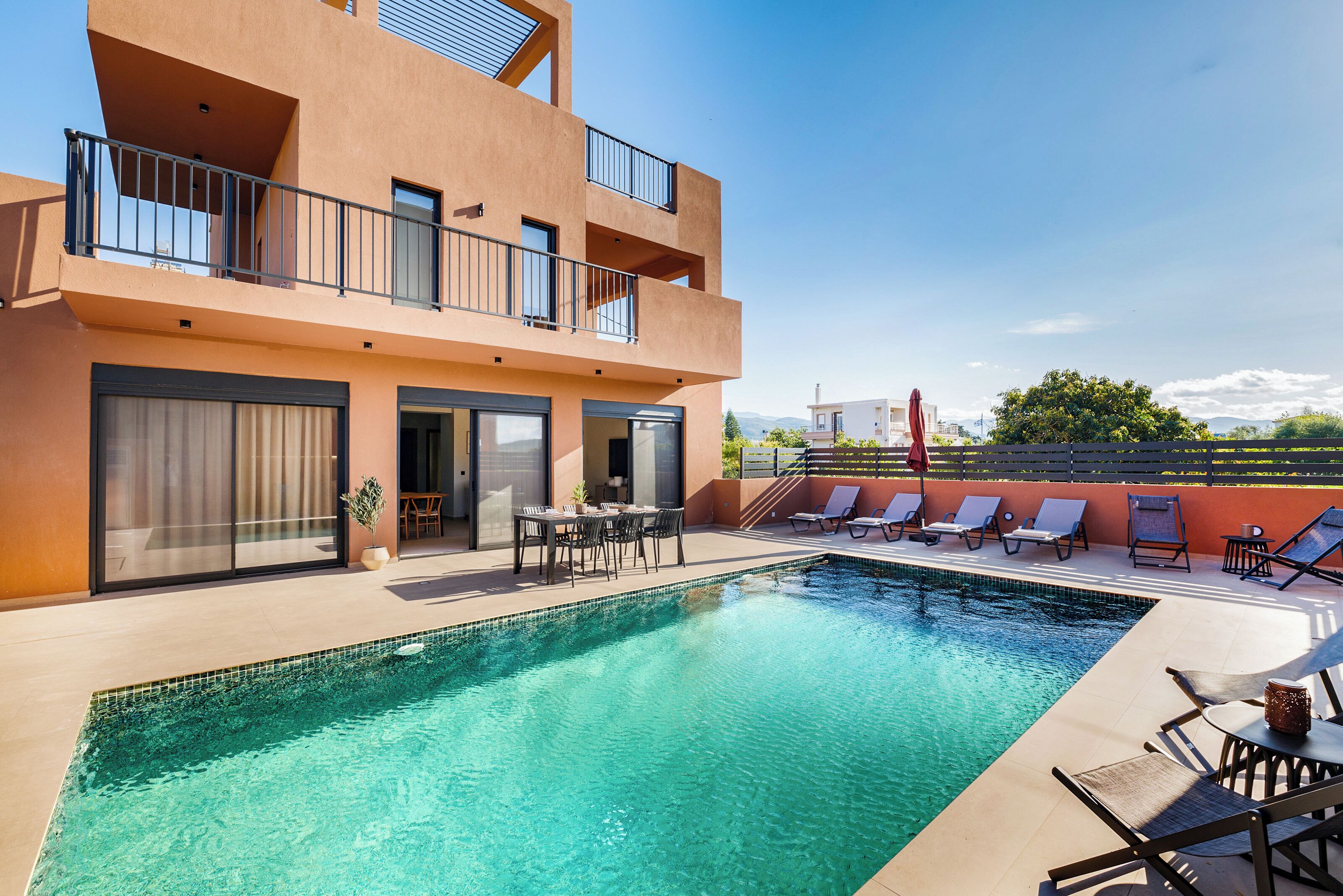 A modern building with a swimming pool, outdoor seating, and a view of the city.