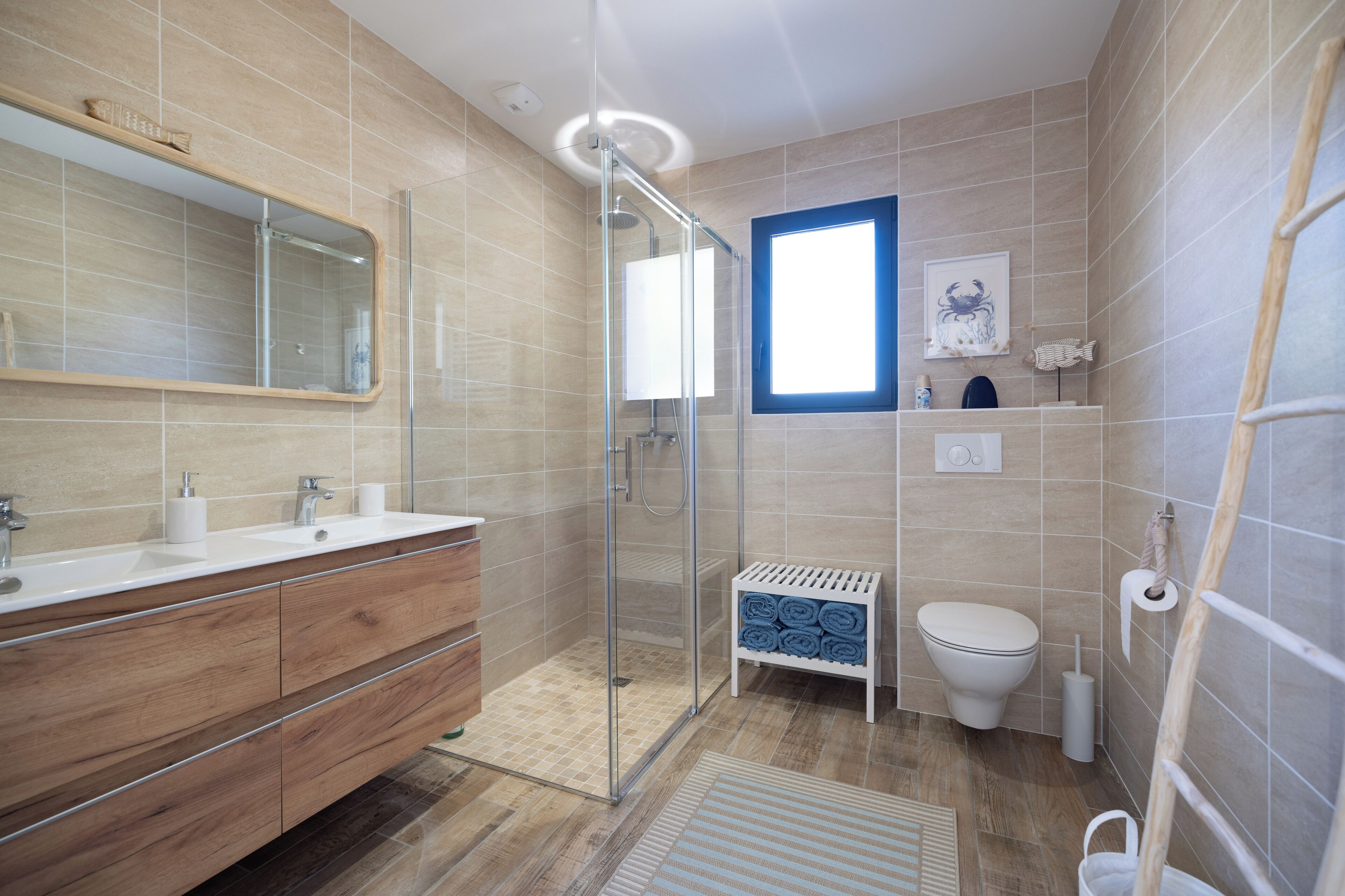 Une salle de bain moderne avec une douche en verre, un meuble-lavabo en bois, des toilettes et une petite fenêtre.