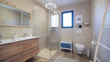 Une salle de bain moderne avec une douche en verre, un meuble-lavabo en bois, des toilettes et une petite fenêtre.