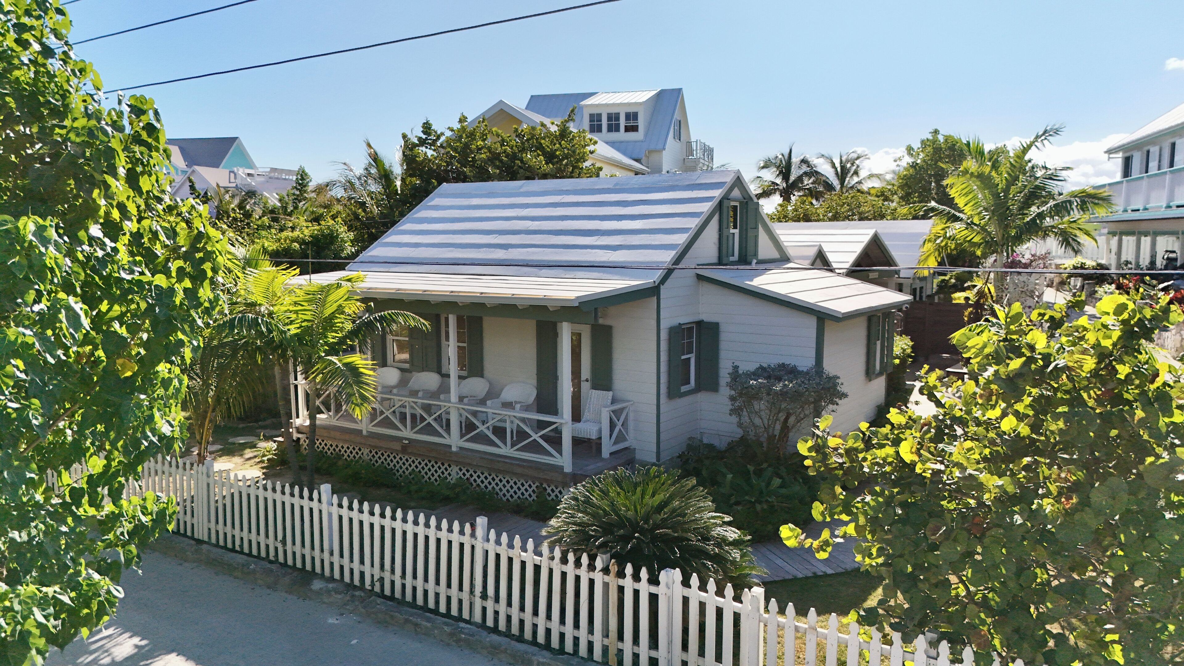A house with a porch, a fenced yard, and a white picket fence.