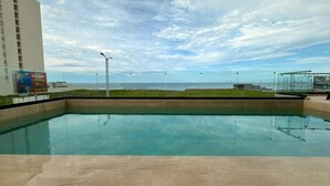 A swimming pool with a view of the ocean and a tall building in the background. - Hotel Makkan Boca (Boca del Río)